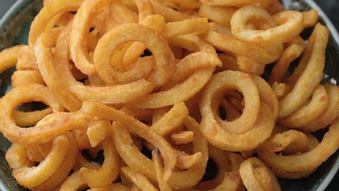 Golden Spicy Seasoned Curly Fries ready to eat. rotating video