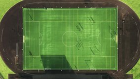 Drone shot of sportsmen training at sports stadium at Sao Jorge island, Azores, Portugal, Europe. Top view of soccer players playing game at green field. Football field with teams exercising together