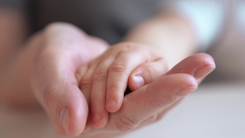 mom holds the hand of a newborn. close-up baby hand. hospital caring happy family medicine concept. baby newborn holding mom hand close-up. mom takes care of the baby in the hospital indoor Royalty-Free Stock Footage #1075943528
