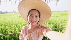 Adult woman making video call showing large rice production field.