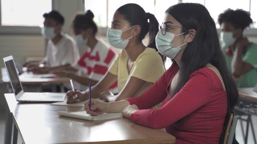 Secondary school students wearing medical face masks writing notes during class at the High School or College. Back to School in Covid Pandemic Royalty-Free Stock Footage #1075950833