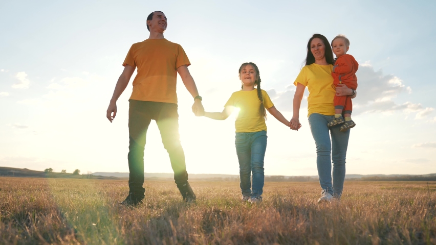Mom, dad and children are happy walking at sunset in the park. Family teamwork. Healthy active lifestyle. Happy family concept and family values. People walk on green grass in the field.