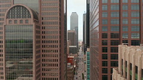 Ascending and tilt down footage of downtown skyscrapers. View along street between tall buildings. Dallas, Texas, US in 2021