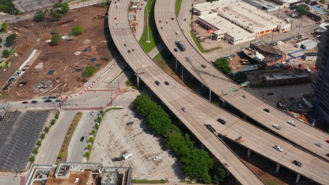 Forwards tilt up reveal of multilane highway heading to interchange. Aerial view of busy main road leading through town. Dallas, Texas, US in 2021