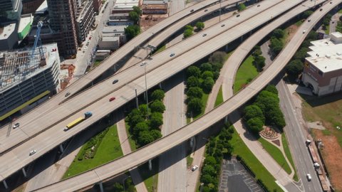 Fly above busy multilane highway interchange. Tilt up reveal of town neighbourhood. Dallas, Texas, US in 2021