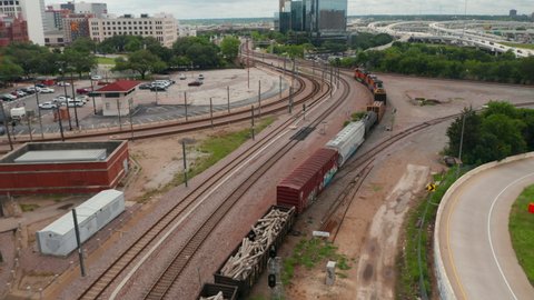 Aerial view of freight train winding on track. Tracking footage of three powerful diesel engines leading train. Transport of goods on railway corridor. Dallas, Texas, US in 2021