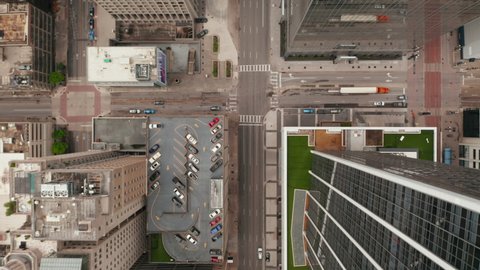 Aerial birds eye overhead top down tracking view of car driving on wide multilane one-way downtown street leading between skyscrapers. Dallas, Texas, US in 2021