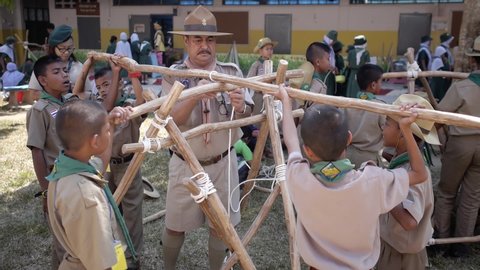 Yala, Thailand March 11, 2016  Thai Boy Scout activities students boys in uniform making wooden catapult learn to build frame, teacher teach how to attach sticks with a rope Ban Yala primary school