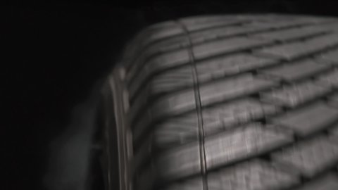 Smoking Tire in a Drift. The spinning wheel rubs against the asphalt and creates a cloud of white smoke on a black background. Filmed at a speed of 120fps