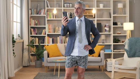 business man in underwear and shirt having a conference call,mature caucasian male works from home using mobile phone to make a work video call