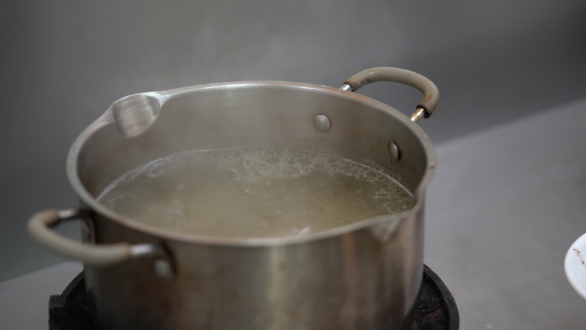 Chicken Broth soup is boiling on the gas strove with a little oil on surface of it.