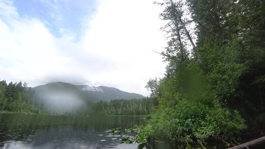 Timelapse of Canadian lake on a rainy day with forest and mountains around