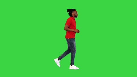 Young african american man in casual clothes runs and takes a look at his watch on a Green Screen, Chroma Key.