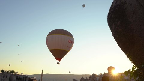 Goreme, Cappadocia, Turkey - May 30, 2021: Ballooning in Kapadokya. Many hot air balloons flying over spectacular breathtaking unusual city streets, valleys and rocks in blue sunrise morning sky