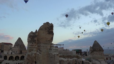 Goreme, Cappadocia, Turkey - May 28, 2021: Ballooning in Kapadokya. Many hot air balloons flying over spectacular breathtaking unusual valleys, rocks and Goreme town in blue sunrise morning sky