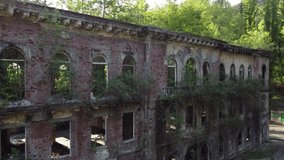 Aerial video from a drone overlooking an abandoned building overgrown with plants in the city of Tkvarcheli in Abkhazia. Textured city in the Caucasus mountains.