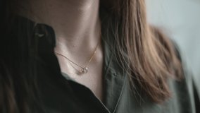 Angry woman brunette with loose hair hand touches gold necklace with pendant and rips off from neck at bright light closeup. - Powered by Shutterstock - Get 15% off with code: PIKWIZARD15
