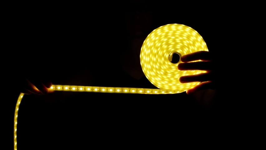 Yellow LED strip coil decorative lighting in hand on dark background. | Shutterstock HD Video #1075982072
