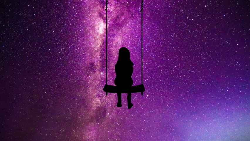 The silhouette of a child on a swing watching the milky way and shooting stars.