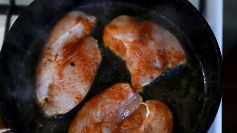 Chicken fillet pieces frying in the pan. Chicken breast sliced fried in oil. Man cooking meat for dinner. Golden crust on chicken meat. Tasty homemade dish.