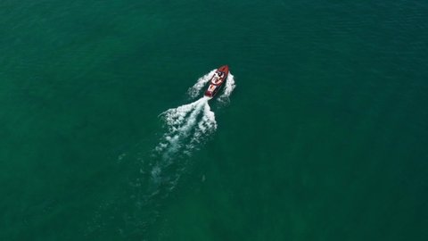 Wooden runabout diagonal movement on the water. Large yacht on the water. Wooden boat top view moves at speed in the reflection of the sun. Drone view of a boat the blue clear waters.