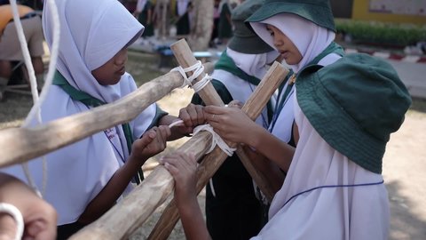 Yala, Thailand March 11, 2016  Thai Boy Scout activities students Muslim girls in uniform making wooden catapult learn to build frame attach sticks with a rope. Ban Yala primary school