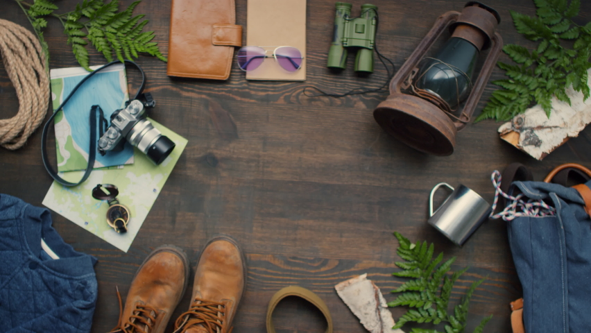 Directly above shot of unrecognizable woman putting passports and airline tickets on wooden table with travel accessories lying on it
