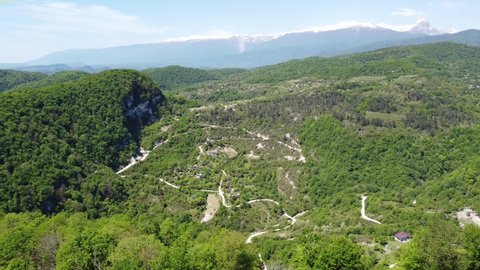 Aerial video from the drone. Bright and luscious mountain landscape on the Black Sea coast in Abkhazia. View of the resort town of Novy Afon and the high Caucasian mountains with glaciers on the horiz