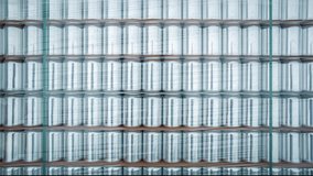 Aluminum beverage cans on shelves in industrial warehouse. Recyclable aluminium metal containers for drinks stored in stack on shelf, filmed with zoom effect