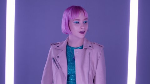 Eccentric woman with pink hair posing near led-colorful neon lamps. Charming odd girl, nightlife concept. Modern model pop outfit, influencer lifestyle.