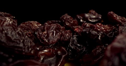 A dry grapes macro shot close-up shot of ripe raisins lies on a table against a black background. Macro close-up shot detailed of raisins. Interesting angle, stock footage.