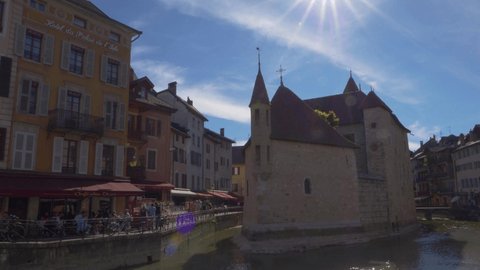 Annecy, France - 30 may, 2021: Static footage of Le Palais de I'Ile and surrounding waterfront, Annecy, France. Fortified house resembles the prow of stone ship in Thiou river.