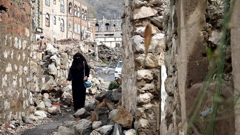 Taiz _ Yemen _ 03 May 2021 : A Yemeni woman walks among the destroyed buildings due to the war in the city of Taiz, Yemen