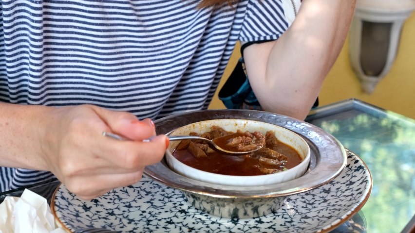 female customer drinking soup in restaurant