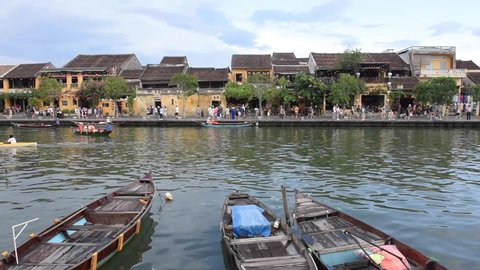 Hoi an,  Vietnam July - 16, 2021: - Wooden boats on the Thu Bon River in Hoi An Ancient Town, Vietnam. Scenic yellow old houses on waterfront reflected in river.