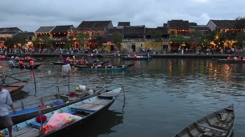 Hoi an,  Vietnam July - 16, 2021: - Wooden boats on the Thu Bon River in Hoi An Ancient Town, Vietnam. Scenic yellow old houses on waterfront reflected in river.