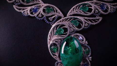 Beautiful necklace with blue sapphires and green emeralds on a black mannequin. Video. Close up of an expensive pendant of white gold and gemstones.