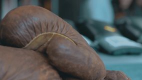 Close up of old brown leather boxing gloves on blurred background. Video. Concept of sport and sports equipment.