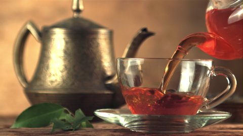 Super slow motion in a glass cup pour black tea. On a brown background.Filmed on a high-speed camera at 1000 fps.