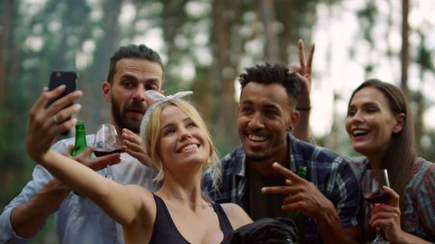 Closeup happy multiracial people posing for self portrait on backyard. Portrait of smiling friends taking selfie photo with dog outdoors. Friendly guys making group photo in summer forest.