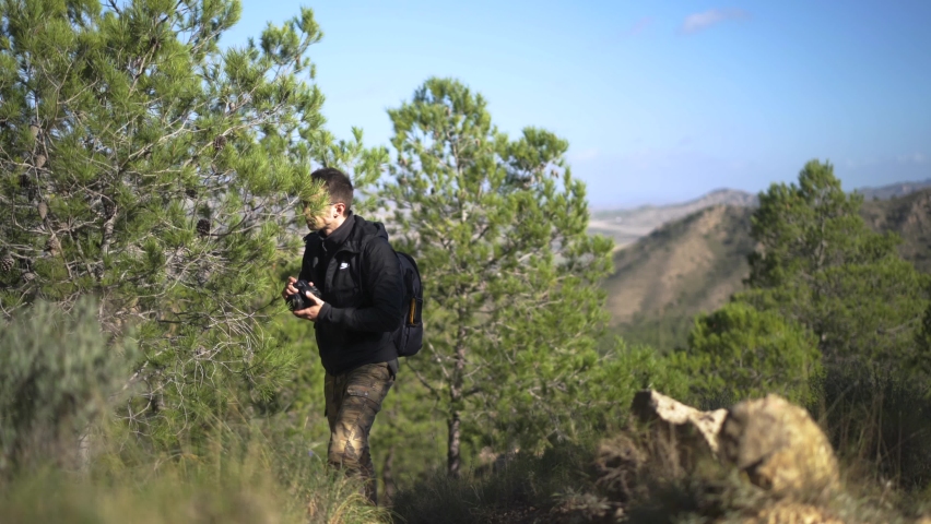 Male hiker taking photographs on mountain trail adventure
