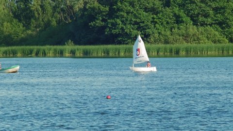 Tourist Cruising On The Optimist Sailing Dinghy At The Lake In Kolbudy In Gdansk County, Poland. wide shot