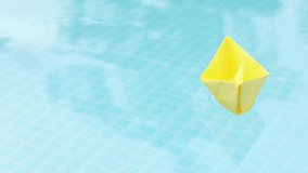 a yellow paper boat floats bobbing on the waves