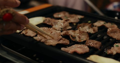 Family enjoy eating pork meat grilled and roasting in hot pan at restaurant. Raw pork on grill in hot pan. Japanese food style.