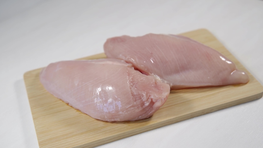 Fresh raw chicken breast on a board. Chicken fillet rotates on the table Royalty-Free Stock Footage #1076037965