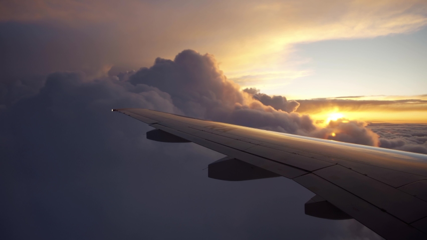 Aerial view of sunrise through airliner window in the morning. Aerial view of Cloudscape in dawn through plane window. Royalty-Free Stock Footage #1076037986