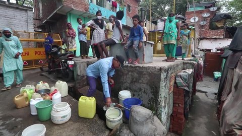 New Delhi, India, July 17, 2021: A man filling drinking water in a 
 plastic bottle as water pot seen in a queue for filling water in summer, provided by Jal Board, for slum area people
