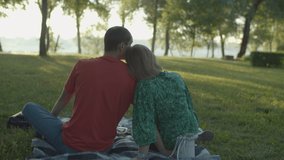 Back view of 30s couple having picnic in the park early in the morning. Steadicam shot of family sitting on the blanket in the park looking at sunrise. - Powered by Shutterstock - Get 15% off with code: PIKWIZARD15