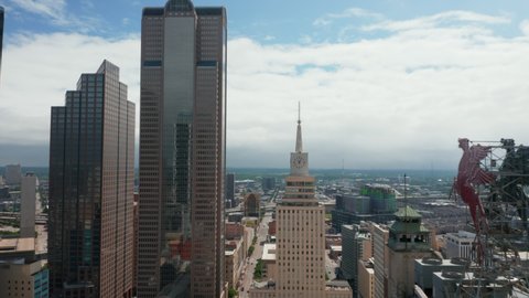 Aerial view of tall building with spike and large clock. Forwards fly to Mercantile National Bank Building. Dallas, Texas, US in 2021