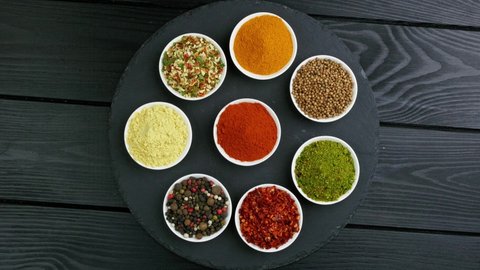 Colorful herbs and spices for cooking. Indian spices. On a black background. Top view